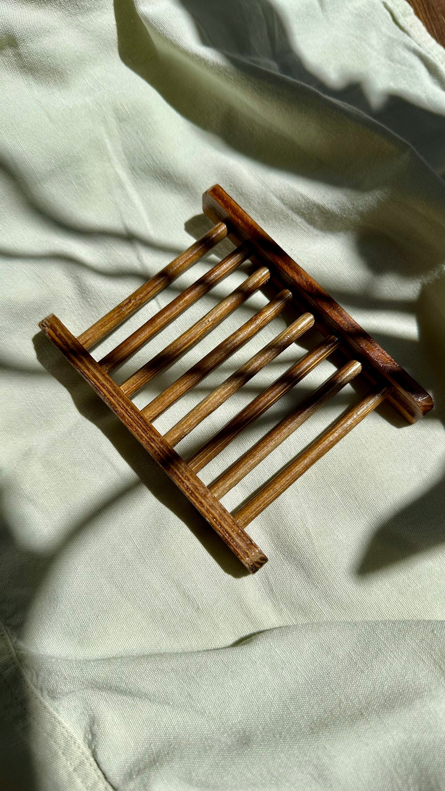 Wooden bamboo soap rack on a light fabric background