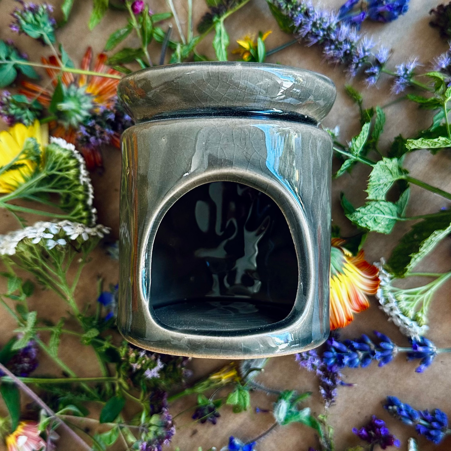 Silver wax warmer with a silhouette design surrounded by colorful flowers on a textured surface