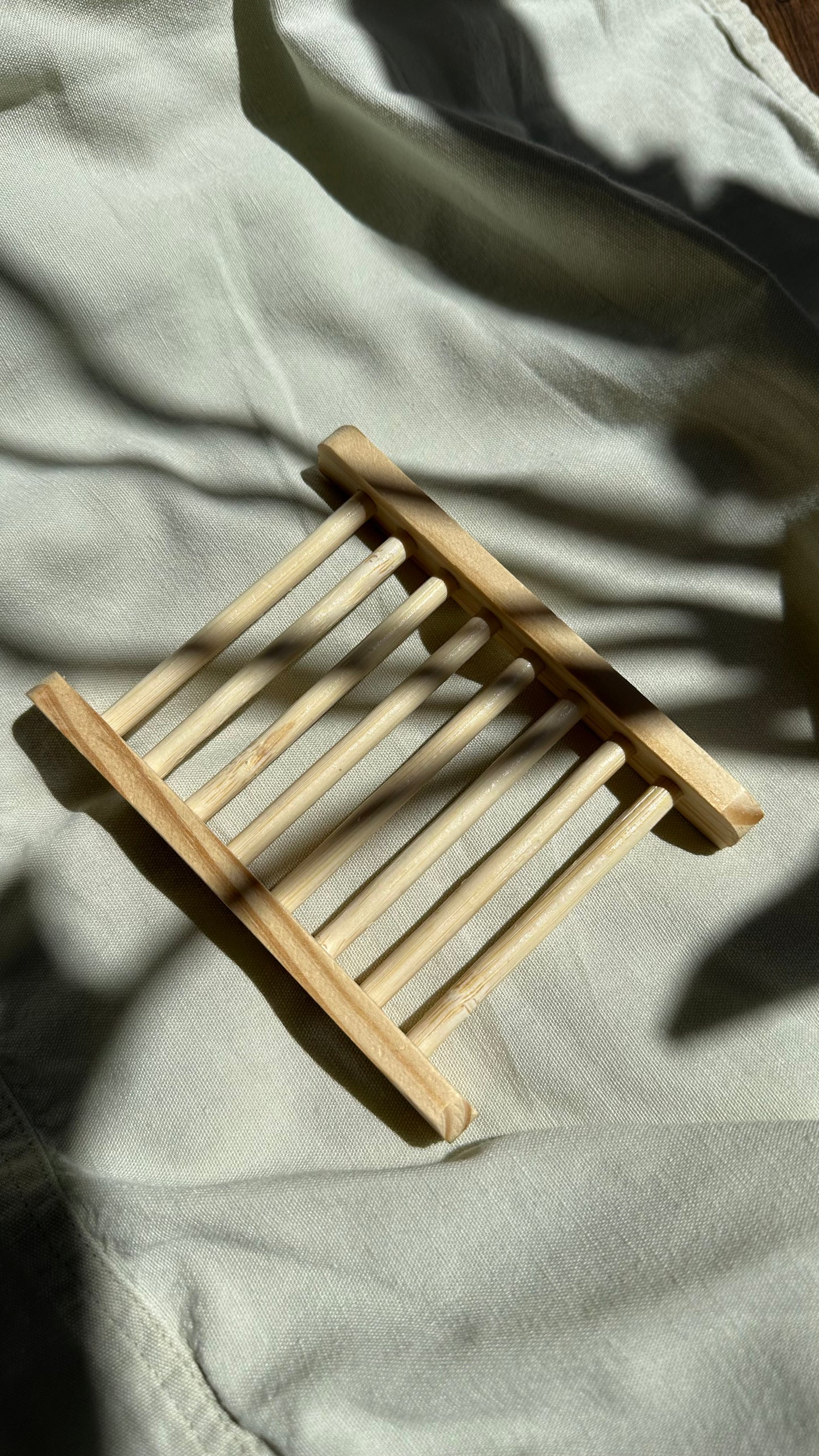 Small wooden stool on a light-colored fabric surface