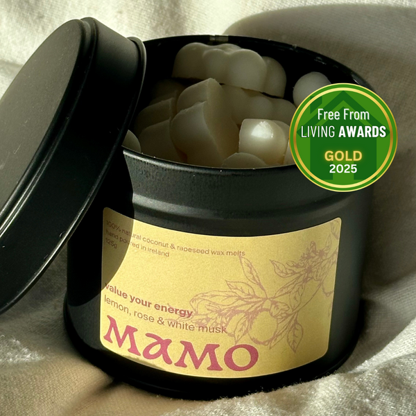 Black container of wax melts with a gold label and 'MAMO' branding, on a light background.