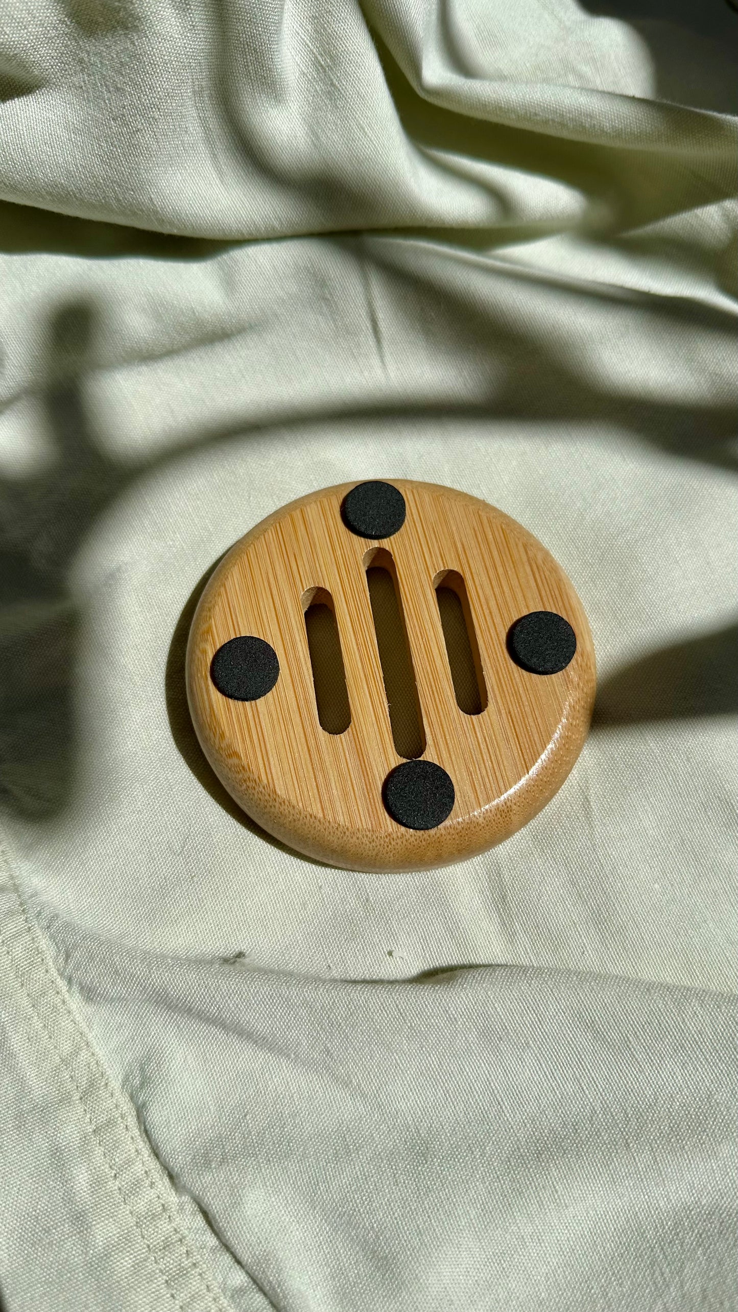 Wooden circular object with black accents on a light fabric background