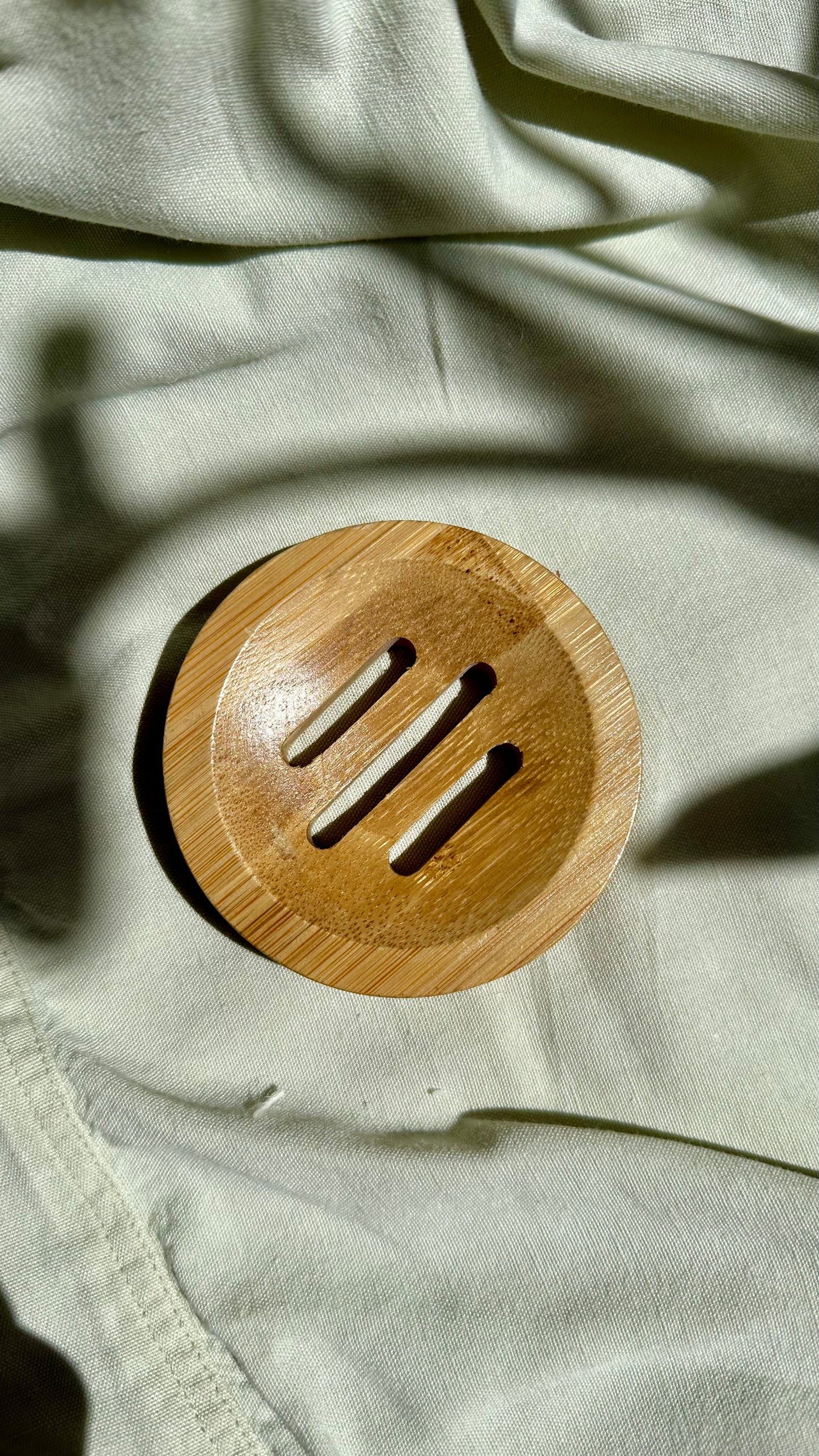 Wooden circular object with slits on a textured fabric background