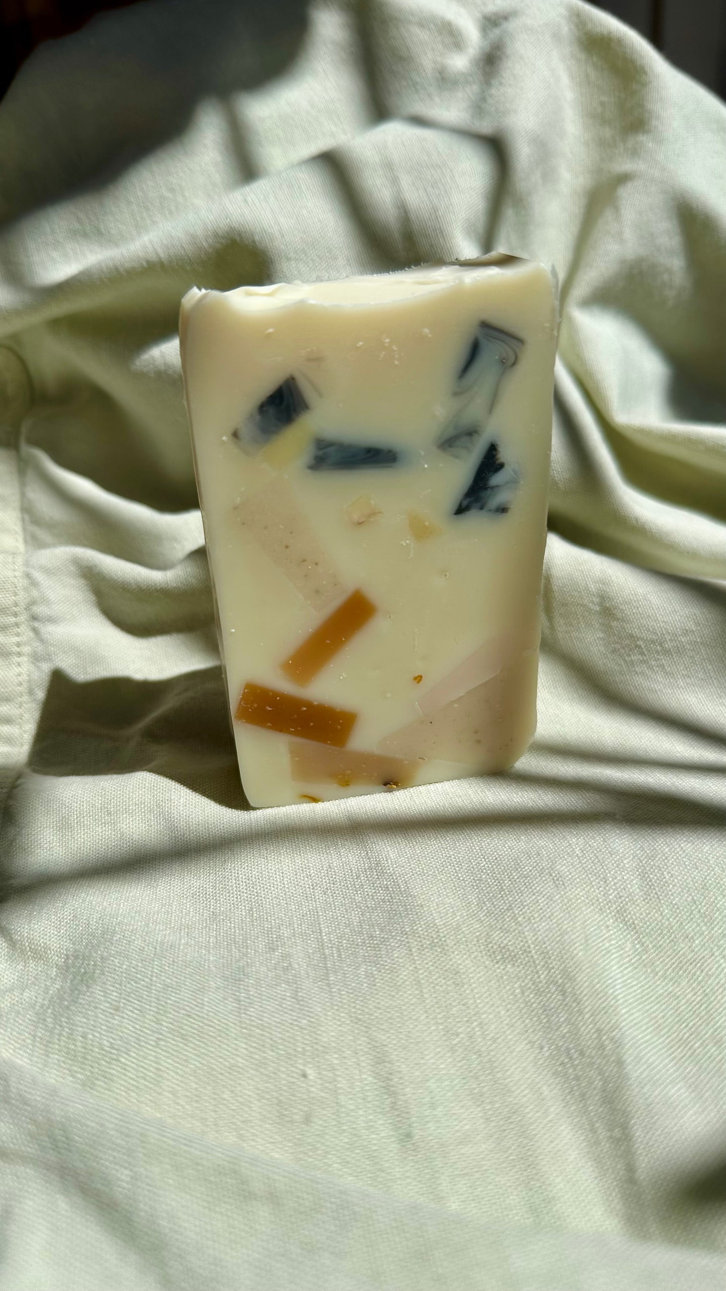 Bar of soap with visible ingredients on a light fabric background