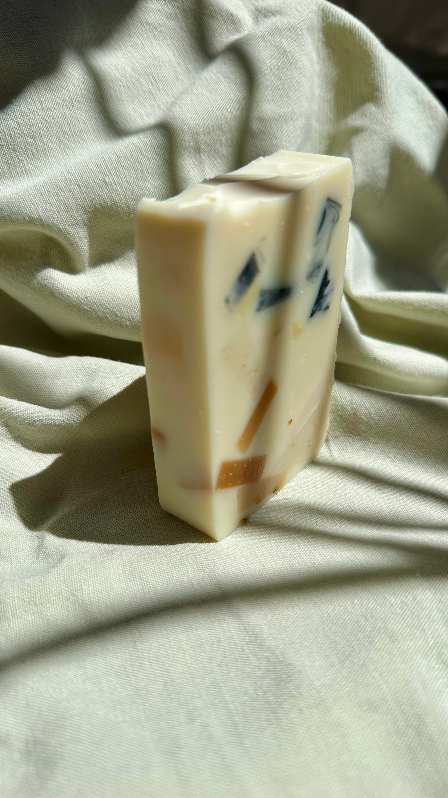 Bar of soap with visible ingredients on a light fabric background