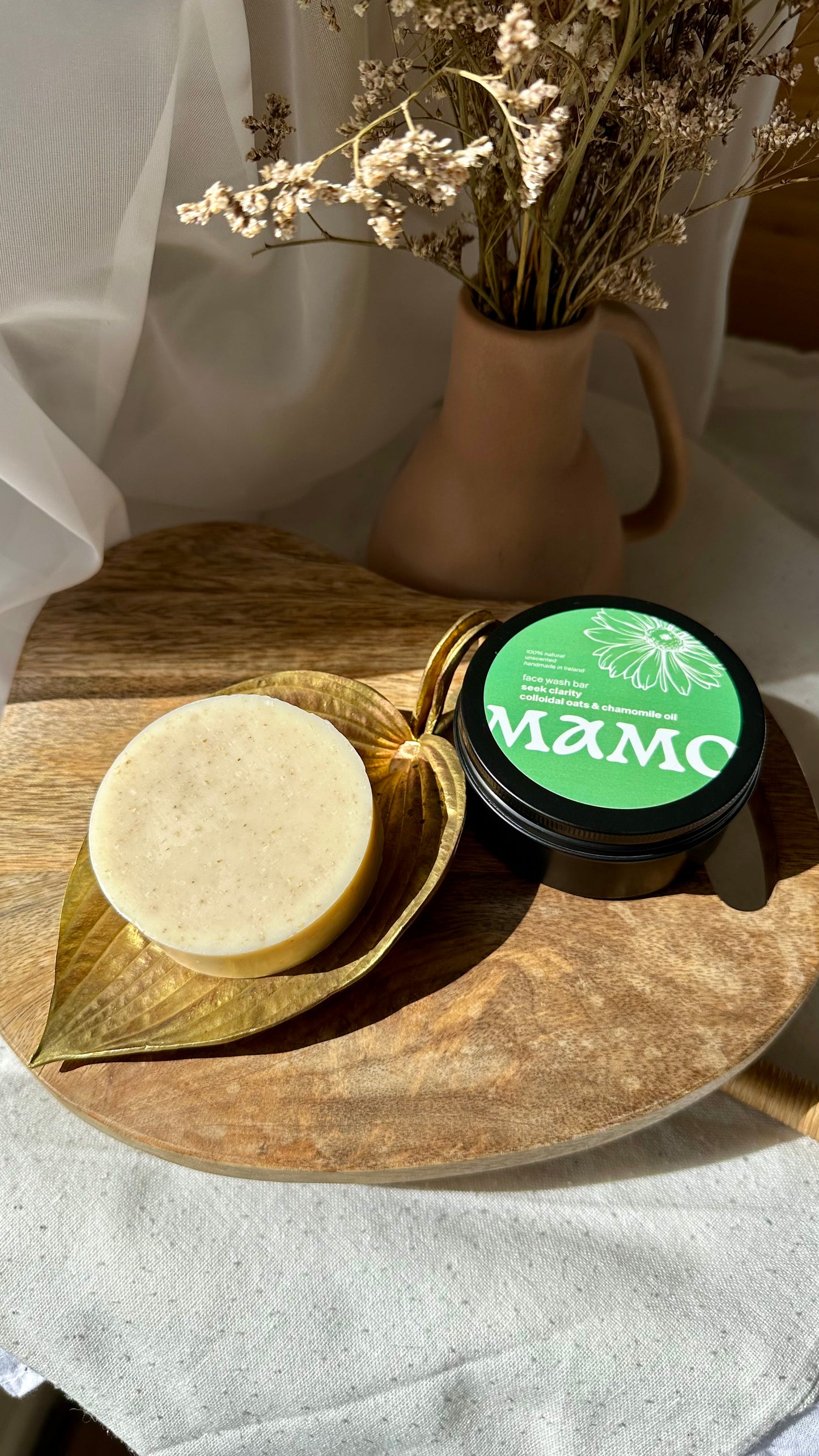 Colloidal oats face soap bar soothing dry and mature skin on wooden tray with linen and a vase
