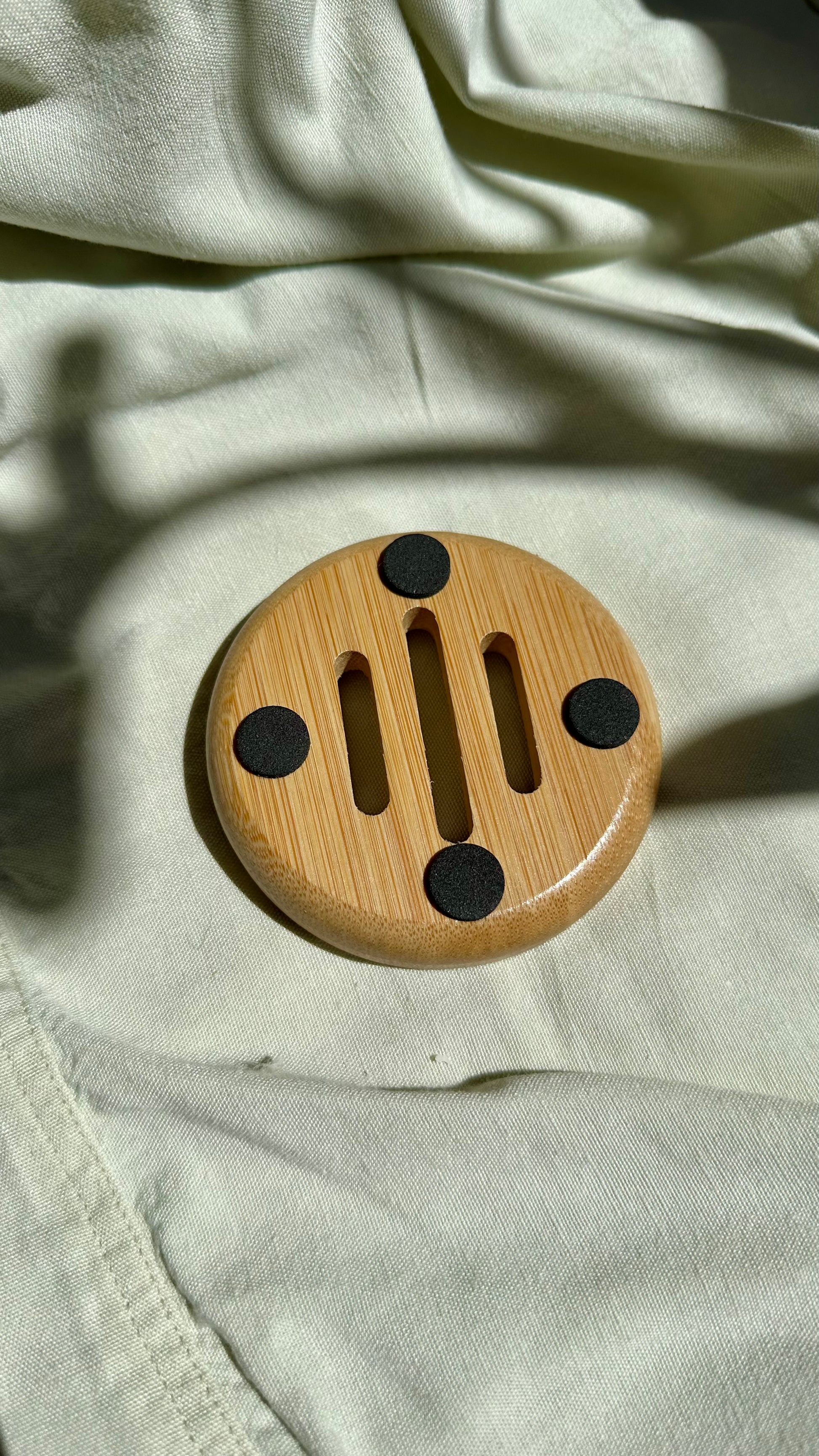Wooden circular object with black accents on a light fabric background
