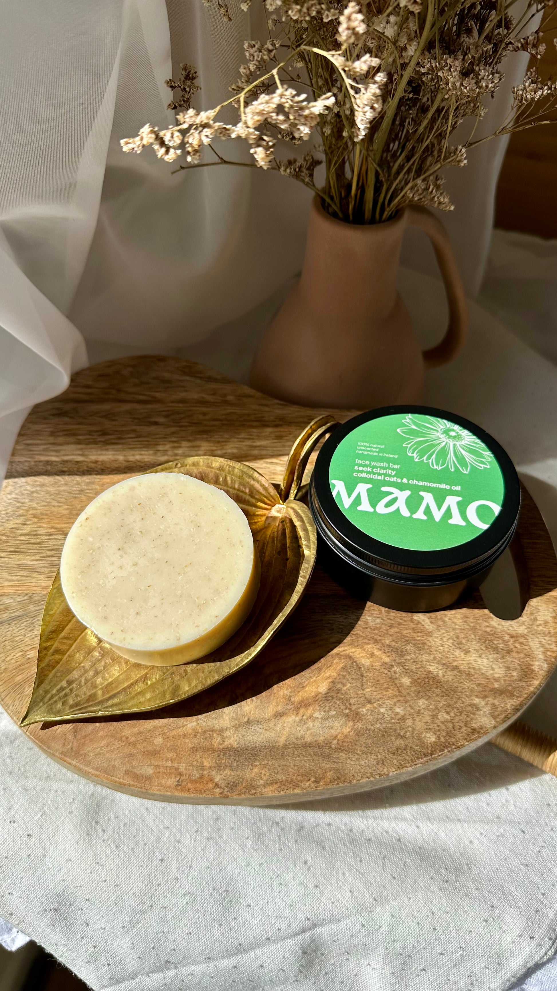 Colloidal oats face soap bar soothing dry and mature skin on wooden tray with linen and a vase