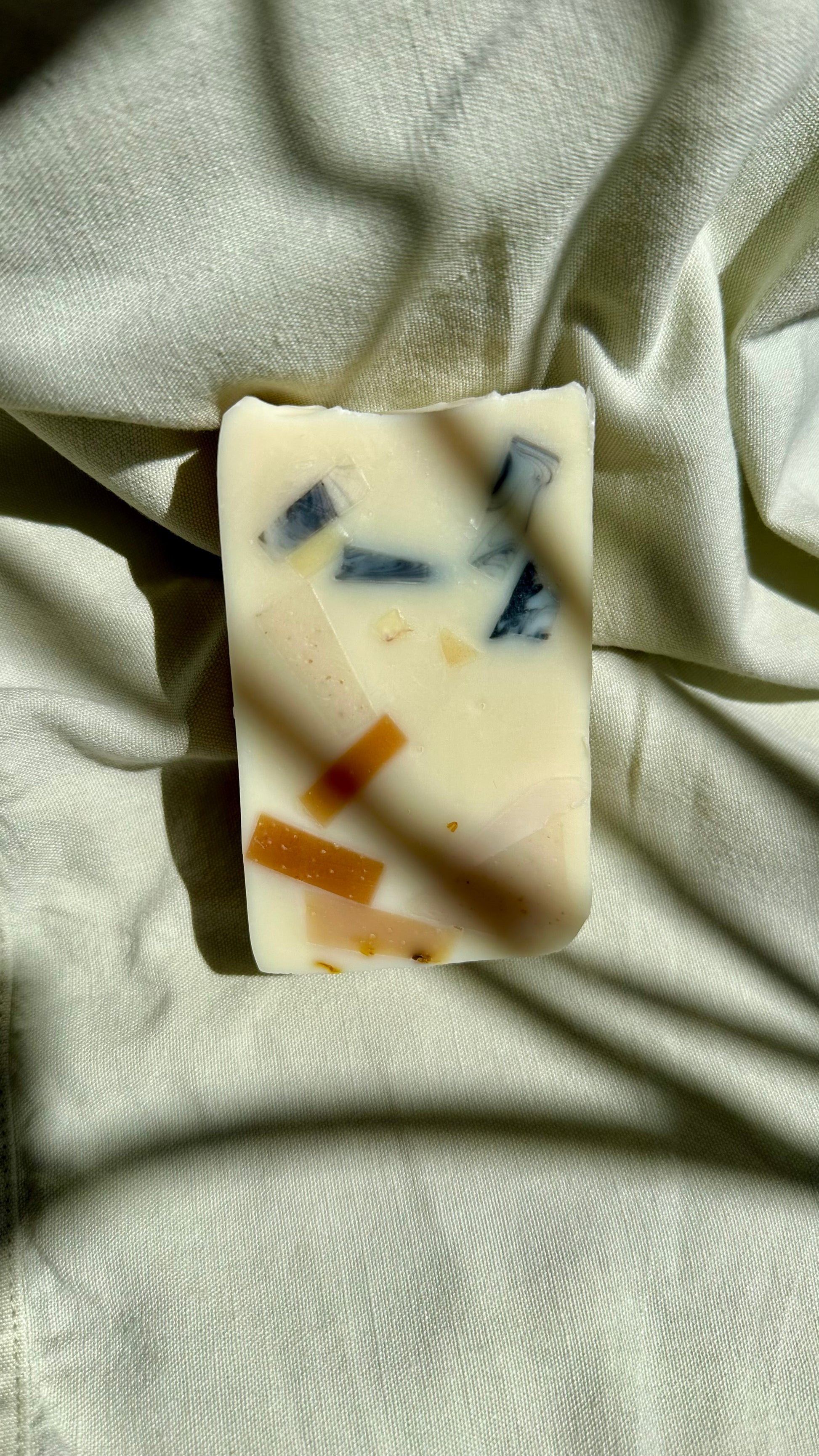 Bar of soap with visible ingredients on a light fabric background