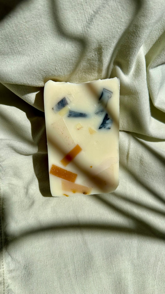 Bar of soap with visible ingredients on a light fabric background